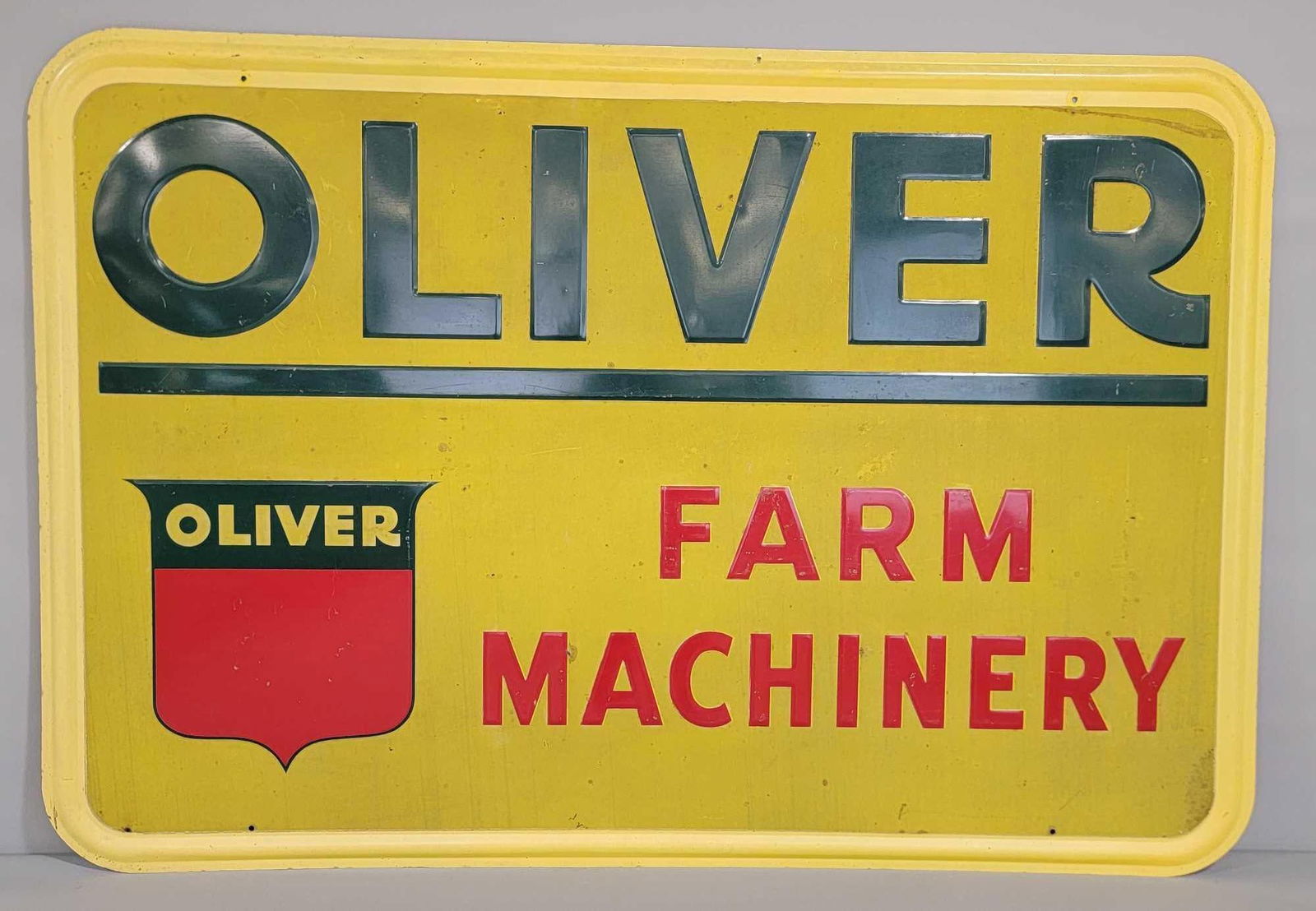 Oliver Farm Machinery w/Red Shield Logo on Yellow Metal Reflective Sign (TAC): rated 8.25, 46"x67.5". This SST self-framed reflective finished sign has good color with soiling commonly seen on reflective signs. Sign has light edge wear. TAC #043146