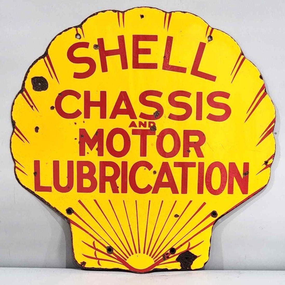 Shell Chassis & Motor Lubrication Porcelain Sign (TAC): rated 8, 25"x24.5", the DSP clam-shaped sign has good color and gloss, has chips in the field and around the perimeter, has two extra nail holes. Rarity 6. TAC #032463