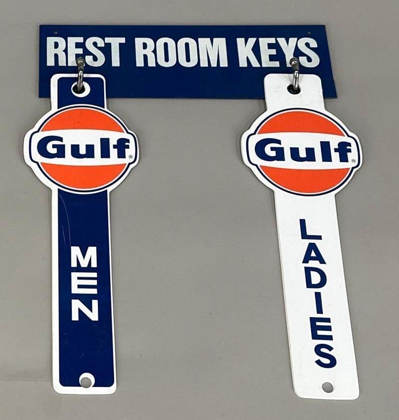 New Old Stock Gulf Rest Room Sign W/ Plastic Key Chains: Rated 9. 8.25" x 11.5". This SST sign with plastic key chains attached has good color and gloss. Top sign shows light bubbling in the paint, plastic key chains show scratches. Rarity 3. TAC # 062056