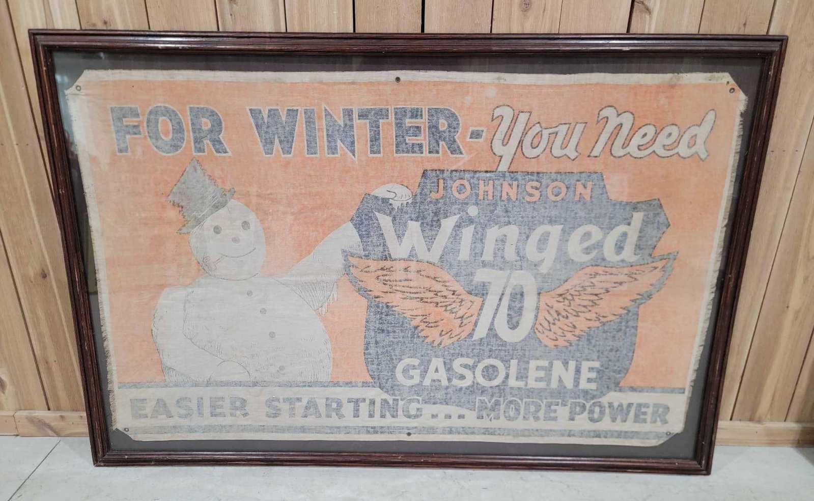 Johnson Winged 70 Gasolene Cloth Banner Framed: rated 7, 62"x41", the cloth banner has wear and is fade, is framed under plexiglass, we will not disassemble.