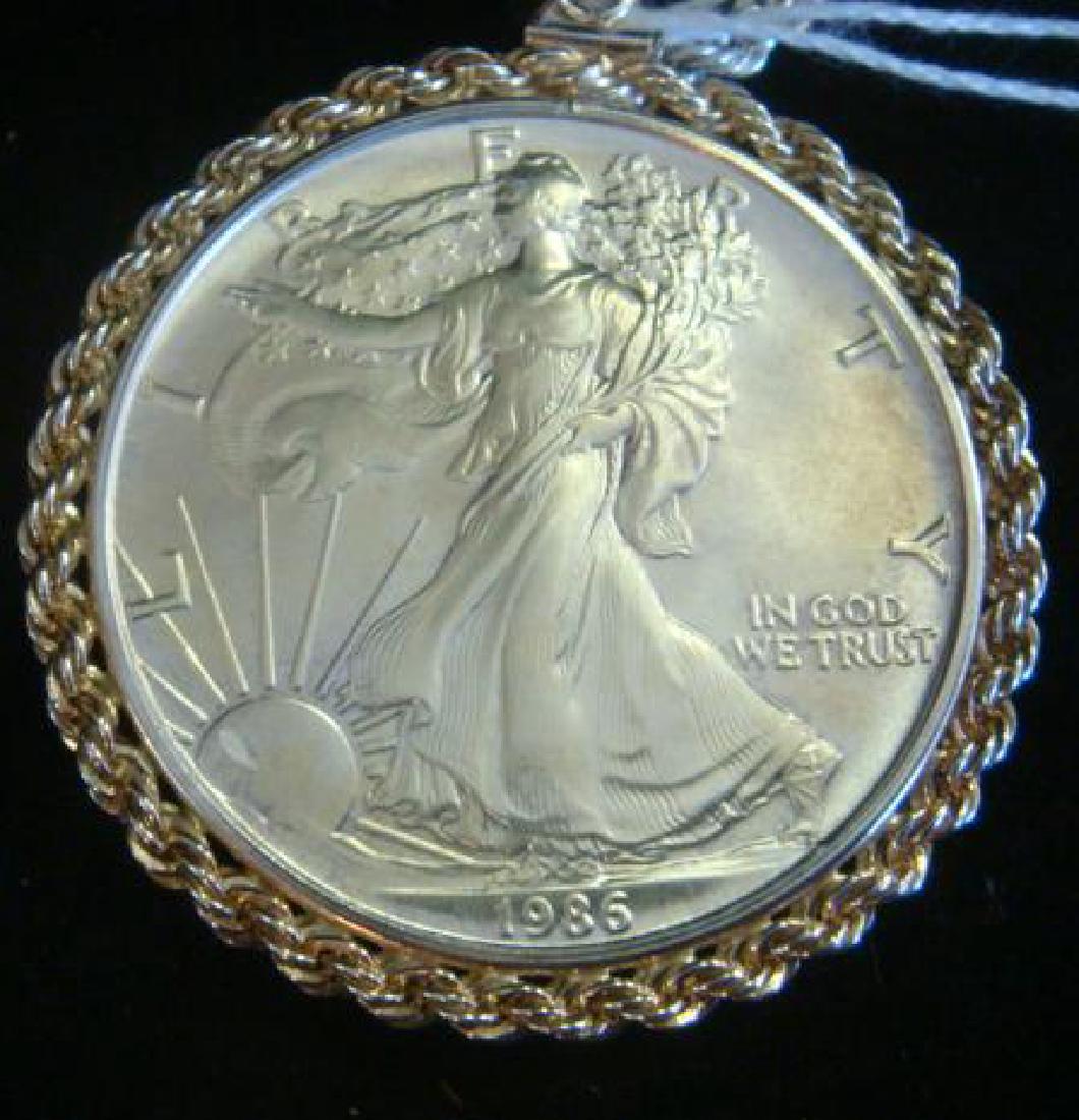 US $1 1986 AMERICAN SILVER EAGLE .999 Pure Silver:: US $1 1986 AMERICAN SILVER EAGLE .999 Pure Silver: Adolph A Weinman's Walking Liberty on Obverse and John Mercanti Eagle on Reverse. 1st year of Issue for this One Ounce Pure Silver Coin. Mounted in S