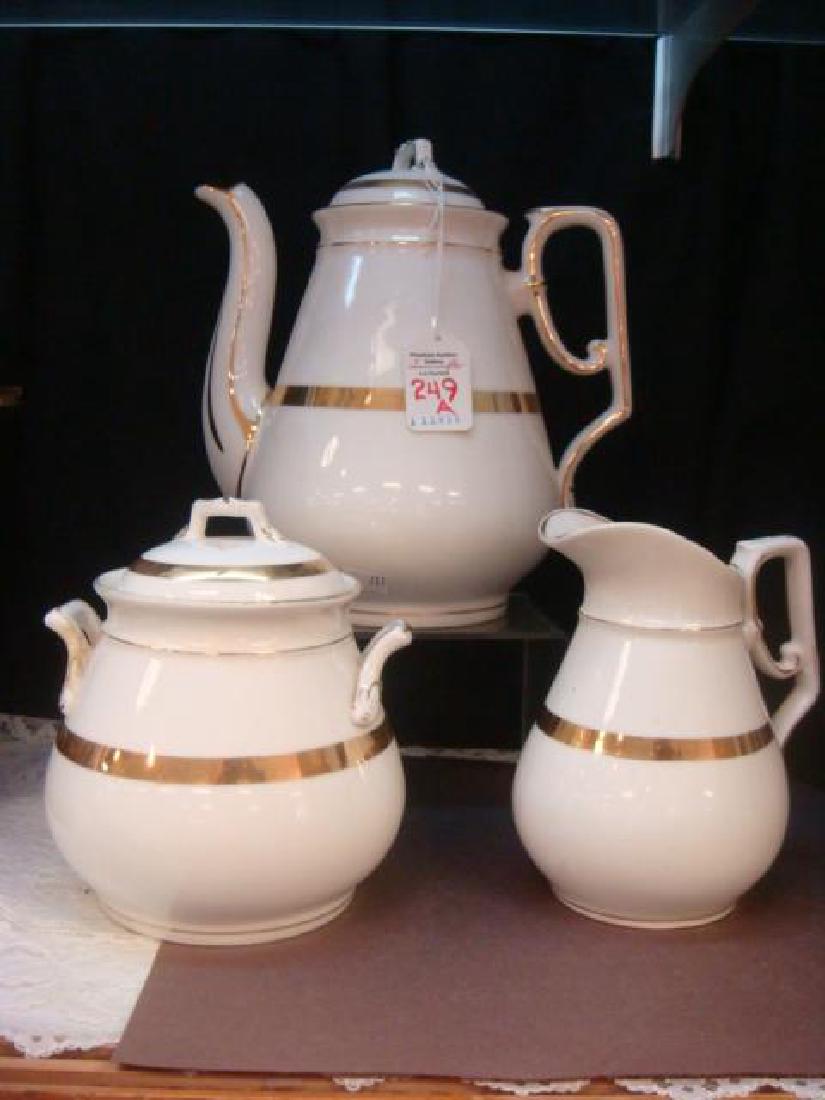 Three Piece C.T. Germany 19thC Tea Set:: Three Piece C.T. Germany 19thC Tea Set: 9" Teapot, 5 3/4" Creamer, 6" Sugar. Cream Color with Gold Bands. Covered Teapot and Sugar, Handled Creamer. Old Repair to One Handle of Sugar. (100-250)