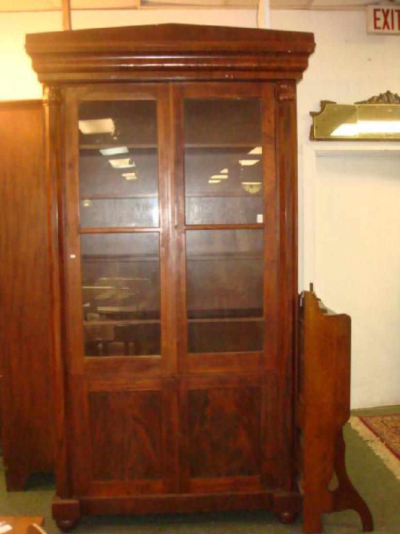 Mahogany Empire Tall Cabinet with 6 Interior Shelves:: Mahogany Empire Tall Cabinet with 6 Interior Shelves: Massive Cabinet with 2 Glass Doors Opening to 5 Interior Shelves. Lower Portion Consists of Double Doors. Paneled Columns with Flame Finials Flank