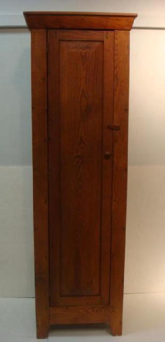 19th C. Red Pine Narrow Shelved Cabinet:: 19th C. Red Pine Narrow Shelved Cabinet: Flat Cornice over Single Chamfered and Paneled Hinged Door. Modified Boot Jack Feet. Interior with 4 Shelves. Hand Forged Nails, Round Knob. (200-400)