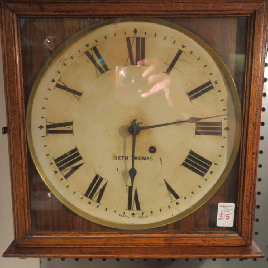 SETH THOMAS Wall Clock:: SETH THOMAS Wall Clock: White Painted Metal Face with Roman Numerals, Pine Case with Glass Door, 15" x 15". (150-300)