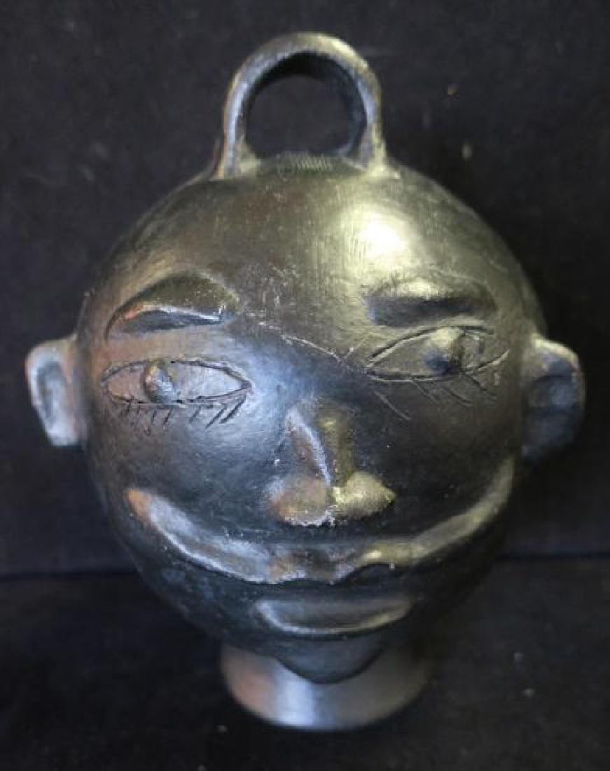 Oaxaka Mexico Black Clay Pottery Face Bank:: Oaxaka Mexico Black Clay Pottery Face Bank: Barro Negro Translated to "Black Mud" Pottery Made in Oaxaka Mexico. Mustached Face with Handle at Top. 91"T. Small Chip on Base. (50-100)