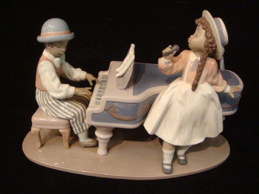 LLADRO "Jazz Duo" Large Figurine:: LLADRO "Jazz Duo" Large Figurine: #5930. Black Legacy Collection. Young Man Playing Piano with Young Lady Singing. One Finger Missing on Piano Player. 8 1/2"T X 12 1/2" X 6 1/4". (200-400)