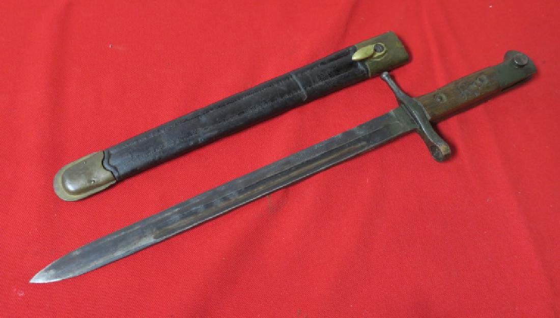 ITALIAN MODEL 1891 "MANNLICHER CARCANO" BAYONET:: ITALIAN MODEL 1891 "MANNLICHER CARCANO" BAYONET: Early Model with Leather Scabbard with Brass Throat and Tip. Mauser Style with Wooden Grips and Press Catch. 11 3/4" Blade with Fuller. Very Good Condi