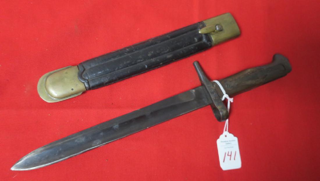 ITALIAN MODEL 1891 "MANNLICHER CARCANO" BAYONET:: ITALIAN MODEL 1891 "MANNLICHER CARCANO" BAYONET: Early Model with Leather Scabbard with Brass Throat and Tip. Mauser Style with Wooden Grips and Press Catch. 9 1/2" Blade with Fuller. Very Good Condit