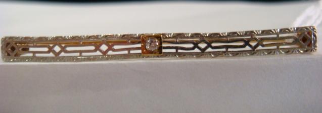 14Kt White Gold Bar Pin with Diamond:: 14Kt White Gold Bar Pin with Diamond: Filigree Box Frame, 2" Long with C-Clasp. Belle Époque Styling with Bezel Set Centered Diamond in Yellow Gold Mount. (150-250)