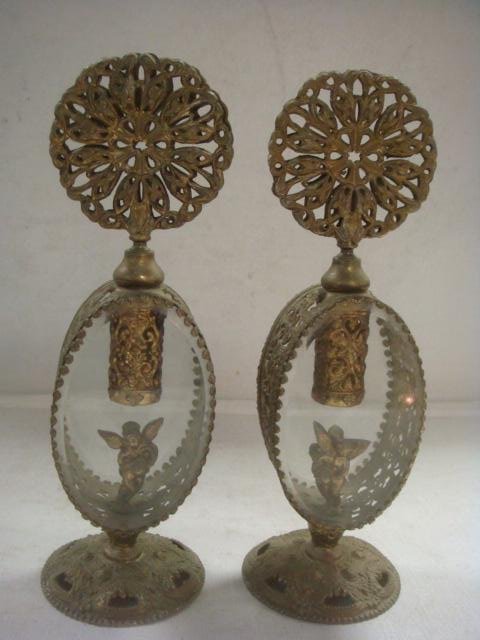 Pair of Matching French Cherub Perfume Bottles:: Pair of Matching French Cherub Perfume Bottles: Oval Glass with Filigree Banded Metal and Stoppers. Internally Mounted with Cherub and Crown. Each is 9" Tall. Round Decorated Brass Foot, No Daubers. (