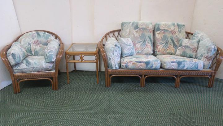 Three Piece Rattan and Floral Sun Room Furniture:: Three Piece Rattan and Floral Sun Room Furniture: Couch with 6 Cushions, 4 Cushion Chair, and a Glass Topped Side Table. Brushed Floral Linen Upholstered Green, Burgundy and Tan On Pillows and Seats. 