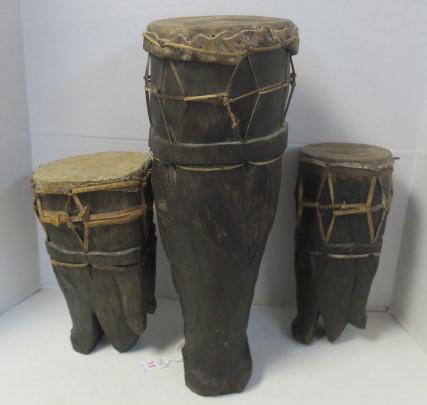 Three Animalistic Hand Carved Tree Trunk Bongo Drums:: Three Animalistic Hand Carved Tree Trunk Bongo Drums: Graduated Sizes for Different Tones. Maybe Alligators or Boars, with Leather Ties to Secure Stretched Drum Head Skin. Smallest 11"T, Medium is 12"