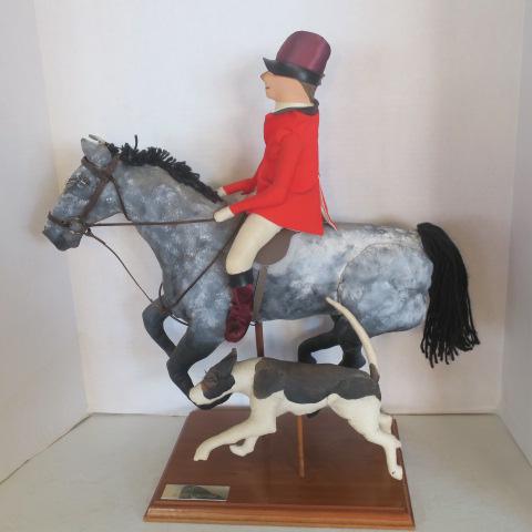 Soft Sculpture of Hunter Astride Dapple Grey Steed:: Soft Sculpture of Hunter Astride Dapple Grey Steed: Artist Audrey Schulz. Fox Hunter in Red Jacket, Boots and Riding Hat. Fox Hound at Side. On Wooden Stand with Brass Tag-Artist Audrey Schulz. Signed