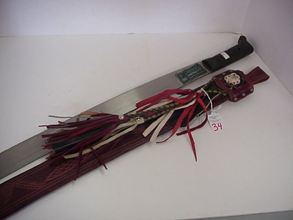 Long Machete With Leather Decorated Scabb: Long Machete With Leather Decorated Scabbard. Modern Black Handled Machete. 33 1/2" Long with Leather Embossed and Tassel Decorated Scabbard.