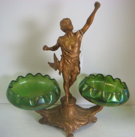 Spelter Figural Compote with Two Art Glass Inserts: Spelter Figural Compote with Two Art Glass Inserts : Hunter Figure at Center Flanked by Iridescent Green Bowls (Likely Loetz). Hunter's Bow/Arrow Missing, Back Foot Broken. (100-200)
