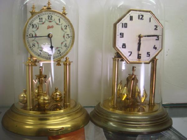 2 KONRAD MAUCH & SCHATZ German Anniversary Clocks:: 2 KONRAD MAUCH & SCHATZ German Anniversary Clocks: 10 1/2"T Clock Marked Konrad Mauch Schweningen A.N Germany. 10 1/2"T Schatrz Clock has Floral Swag Between Numbers. Glass Domes. Both Need Pendulums 