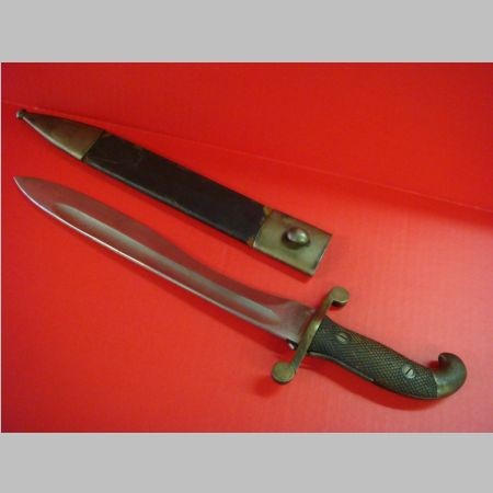 Spanish Bolo Machete ARTILLERIA Fca NACIONAL TOLEDO: Spanish Bolo Machete ARTILLERIA Fca NACIONAL TOLEDO: Very Fine Military Bolo with Checked Wood Grips, Curved Pommel & T Hilt. Locking Leather Scabbard Metal Fittings and Belt Loop Holder. 12" Chopper