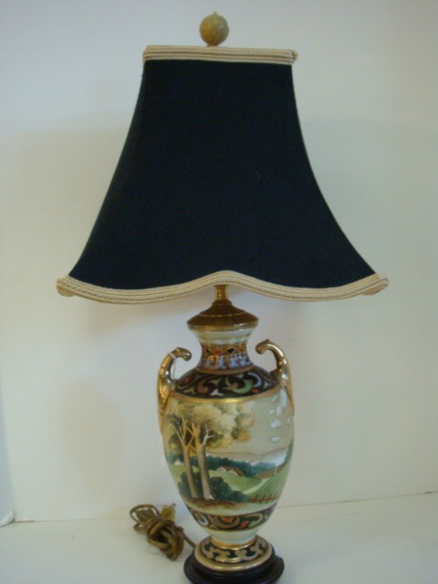 Handpainted NIPPON Scenic Porcelain Lamp with Shad: Handpainted NIPPON Scenic Porcelain Lamp with Shade: 23"T Urn Shaped Body with Double Handles on Round Wooden Plinth. Squared Cloth Shade with Braid Trim and Carved Jade Finial. Landscape Surrounds La