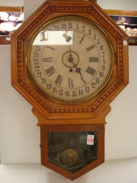 GILBERT "Admiral" Oak Case Octagonal Wall Clock: GILBERT "Admiral" Oak Case Octagonal Wall Clock: 8 Day, 1/2 Hour Strike. Short Drop School Timepiece. Roman Numeral Hours Surrounded by Arabic Numerals for Calendar. Key & Pendulum Present. Ca. 1925.