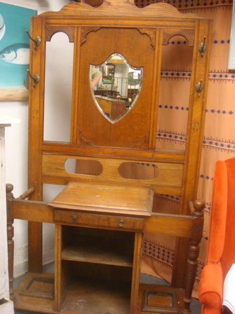 Oak Single Drawer Hall Tree with Shield Mirror: Oak Single Drawer Hall Tree with Shield Mirror: Ca. 1900. Beveled Shield Mirror and Four Side Hooks. Center Drawer over Open Shelved Compartment. Umbrella and Cane Holders at Sides. Considerable Detai