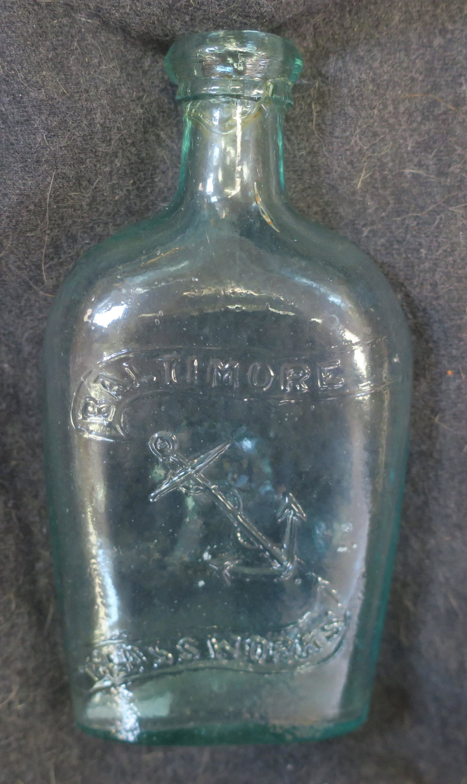 BALTIMORE GLASS WORKS Pennant Flask with Anchor:: BALTIMORE GLASS WORKS Pennant Flask with Anchor: GXIII-49, CA 1850's. Anchor on One Side with Logo and Wheat Sheaf on Reverse. Applied Collared Mouth. 6"T. Mold Blown with Air Bubbles. Very Good Condi