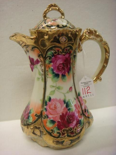 Handpainted NIPPON Chocolate Pot: Handpainted NIPPON Chocolate Pot: Lobed Pot is 10"T with Handpainted Roses and Heavy Gold Accents and Beading on Ivory Ground. Lid has Hairline Crack. Blue Maple Leaf Mark. (100-200)