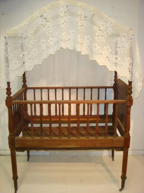 19th C. Walnut Tall Canopy Crib:: 19th C. Walnut Tall Canopy Crib: 48"L X 30"W X 80"T. Delicate Hand Carved Spindle with One Drop Side. Arched Slat Top Fits Over Pegs. Has Appropriate Age Wear and Restoration. (400-800)