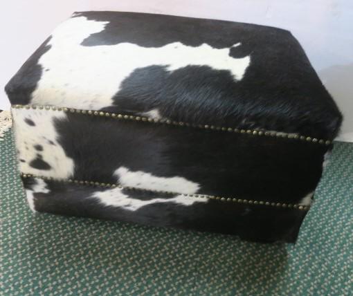 Brown and White Rectangular Cowhide Ottoman:: Brown and White Rectangular Cowhide Ottoman: Each Piece is Unique. Chocolate and White with Double Rim of Brad Trim. Stands on Trapezoid Shaped Wooden Feet. Top Measures 28" X 23". 18"T (400-600)