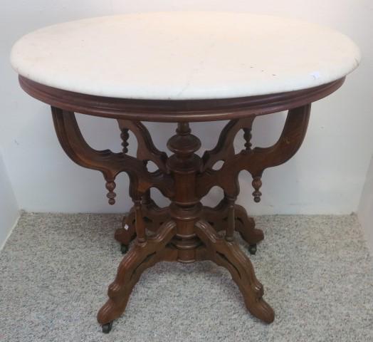 Oval Eastlake Side Table:: Oval Eastlake Side Table: Ornate Walnut Carved Base with Drop Finials and Acorn Center Finial. Metal Casters. Oval White Marble Top with Rounded Edges. 28"T, 26 1/2" X 20". (300-500)