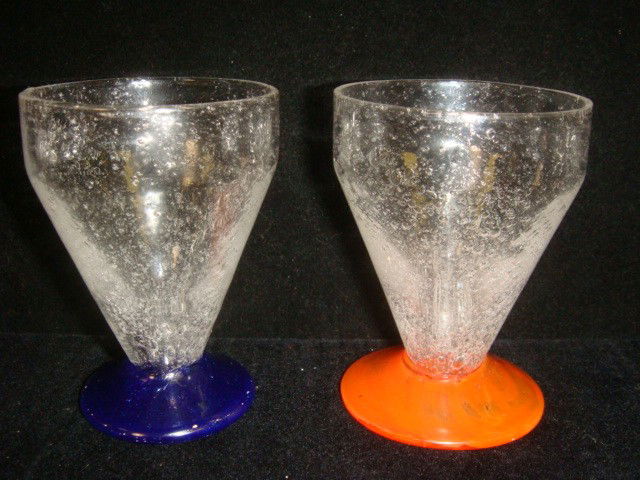 Two Signed DAUM NANCY FRANCE Blown Glass Cordials: Two Signed DAUM NANCY FRANCE Blown Glass Cordials: Each 3"T Cone Shaped Cordial has Bubbles in Clear Glass with One having Blue Foot and the Other with Orange Foot. Name Written on Bottom of Each with