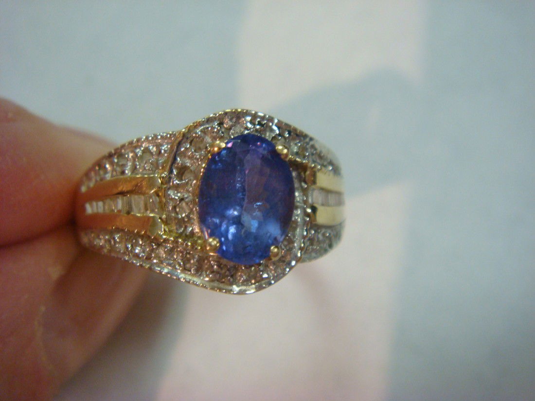 14KT Tanzanite and Diamond Ladies Ring: 14KT Tanzanite and Diamond Ladies Ring: Size 8 1/2, 3/1 dwt. Has Center 1.35 Oval Faceted Tanzanite Surrounded by Round Diamonds and Baguette, Total .75 CT. Set in Yellow Gold with Pierced Bridge. (80