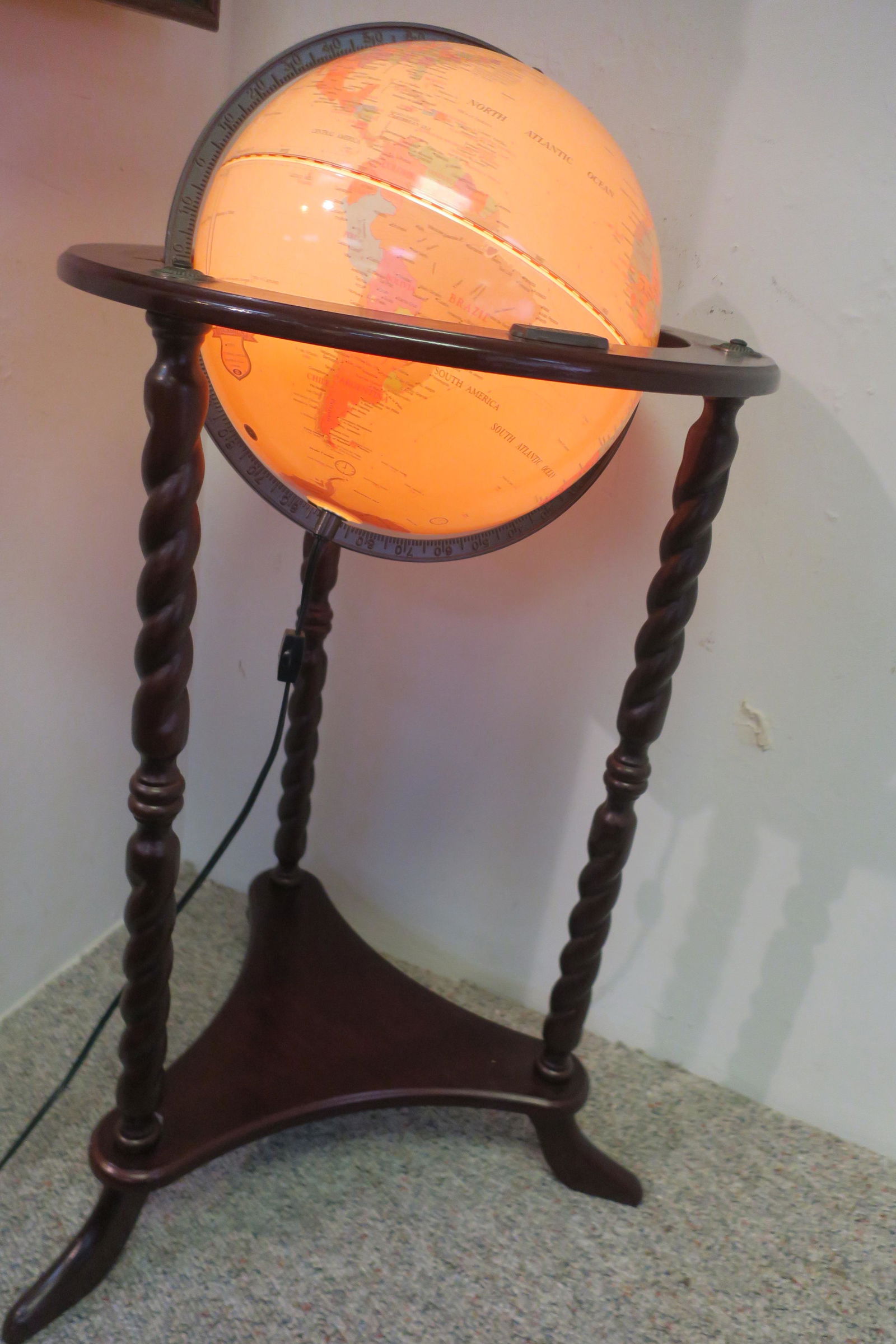 THOMAS PACCONI Light-Up World Globe on Stand:: THOMAS PACCONI Light-Up World Globe on Stand: Electric Light Up World Globe on a Wooden Three Legged Spiral Turned Stand. Label "Thomas Pacconi 1900-2000 Classics". Approximately 35" Tall. (200-400)