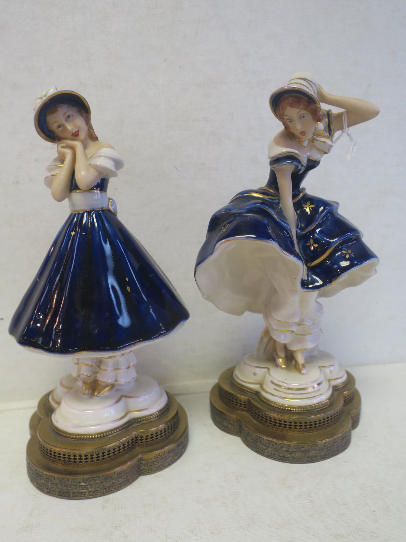 Two Japanese Moriyama Female Figurines:: Two Japanese Moriyama Female Figurines: Porcelain Ladies with Cobalt Glaze Dresses, White Pantaloons and Gold Accents, In the Manner of Royal Dux. Lobed Double Brass Base Duplicating the Base They Sta