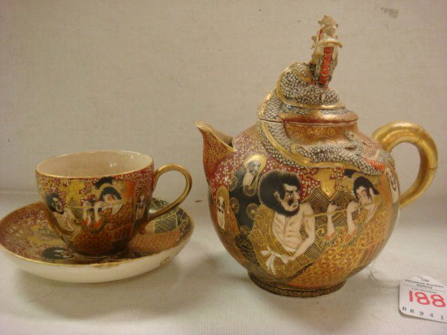 Satsuma Earthenware Teapot, Cup and Saucer: Satsuma Earthenware Teapot, Cup and Saucer: Teapot is 5 1/2"T with Coiled Dragon Finial. Hand Painted Figures on Pot with Relief Dragon Body. Matching 1 3/4"T Teacup and Saucer. Repair to Teapot Handl
