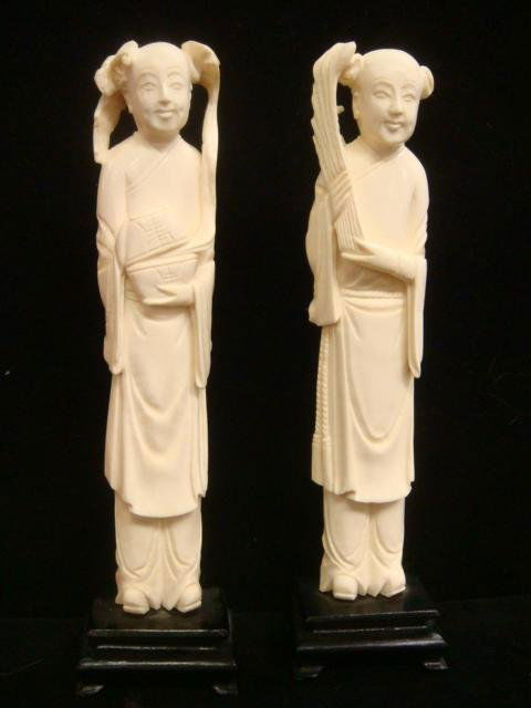 Two Handcarved Ivory Male Figures: Two Handcarved Ivory Male Figures: 8"T Overall on Original Stands. One Male Holds Basket with Emerging Flower Form and Bat on His Head. Other Man Holds Folding Wheat Fan. Both Dressed in Layered Robes