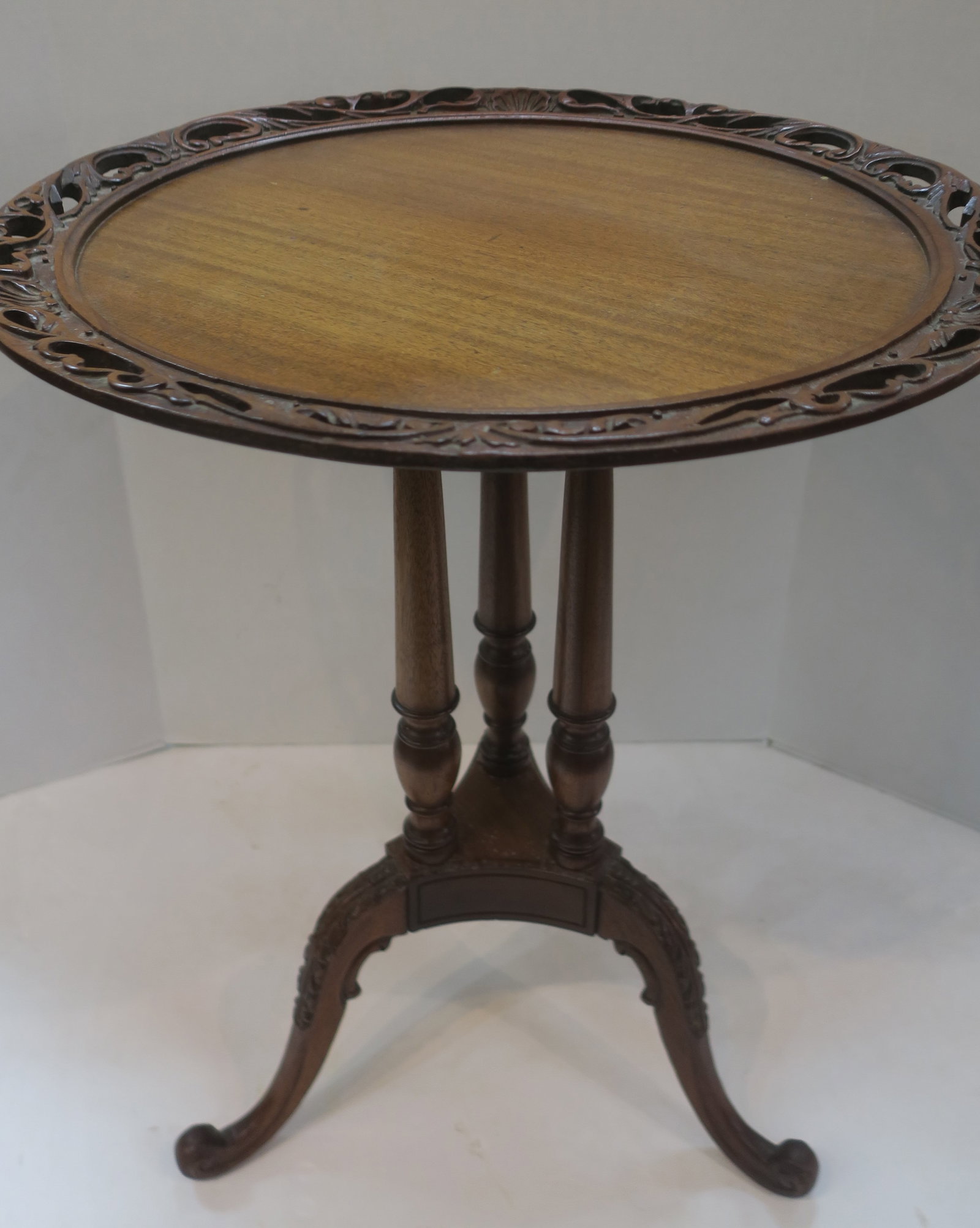 Mahogany Piece Crust Pierced Edge Side Table:: Mahogany Piece Crust Pierced Edge Side Table: Carved, Pierced Edge with Shell and Scroll Pattern. Three Curved Legs Ending in Snail Feet, Leaf Carved Knees. Three Turned Supports. 26 1/2"T, 21 1/4"D. 