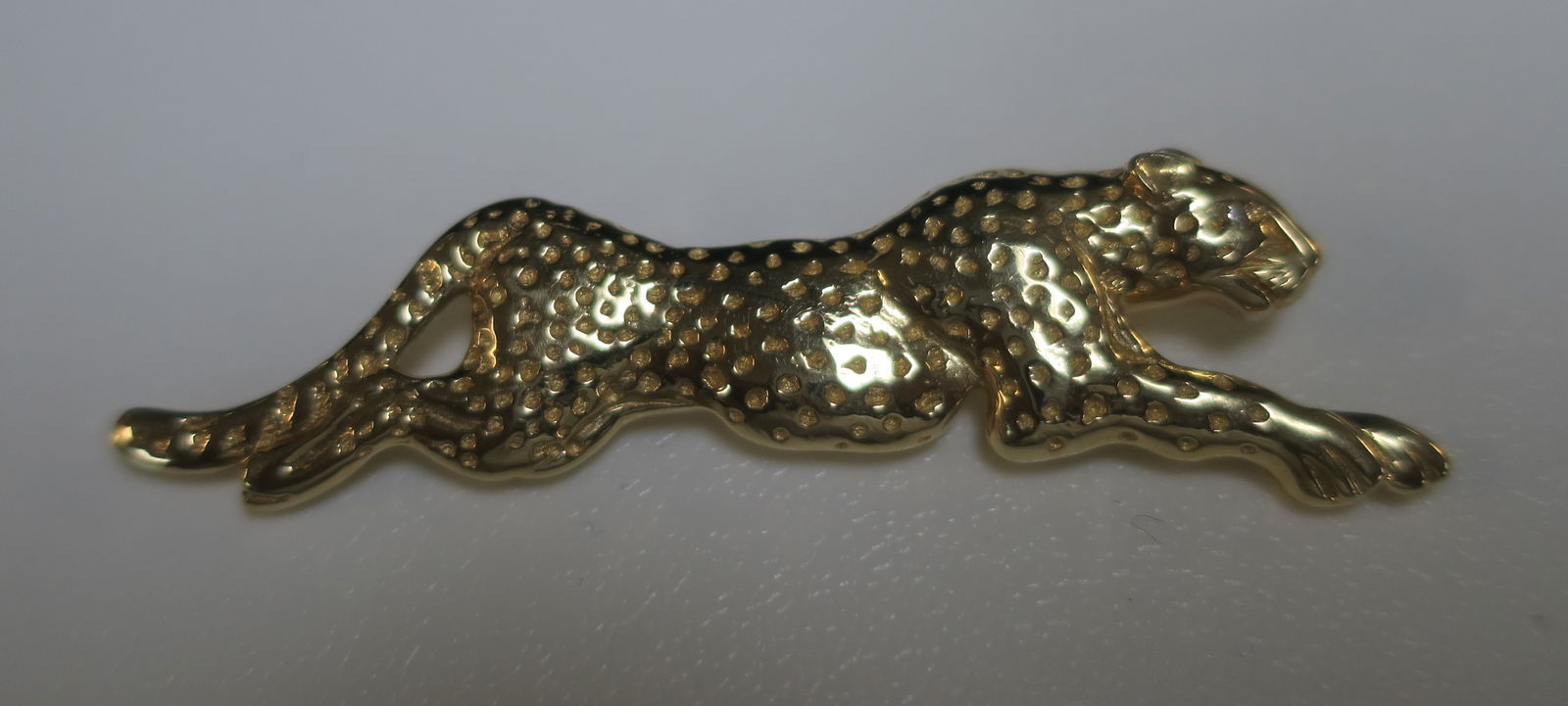 14KT Yellow Gold Coursing Leopard Pin:: 14KT Yellow Gold Coursing Leopard Pin: Marked 14Kt JM. Exotic Cat is a 3D Design with Extended Body and Indented Spots. 2 1/4"L. Polished Finish with Roll Over Pin Clasp. (400-800)