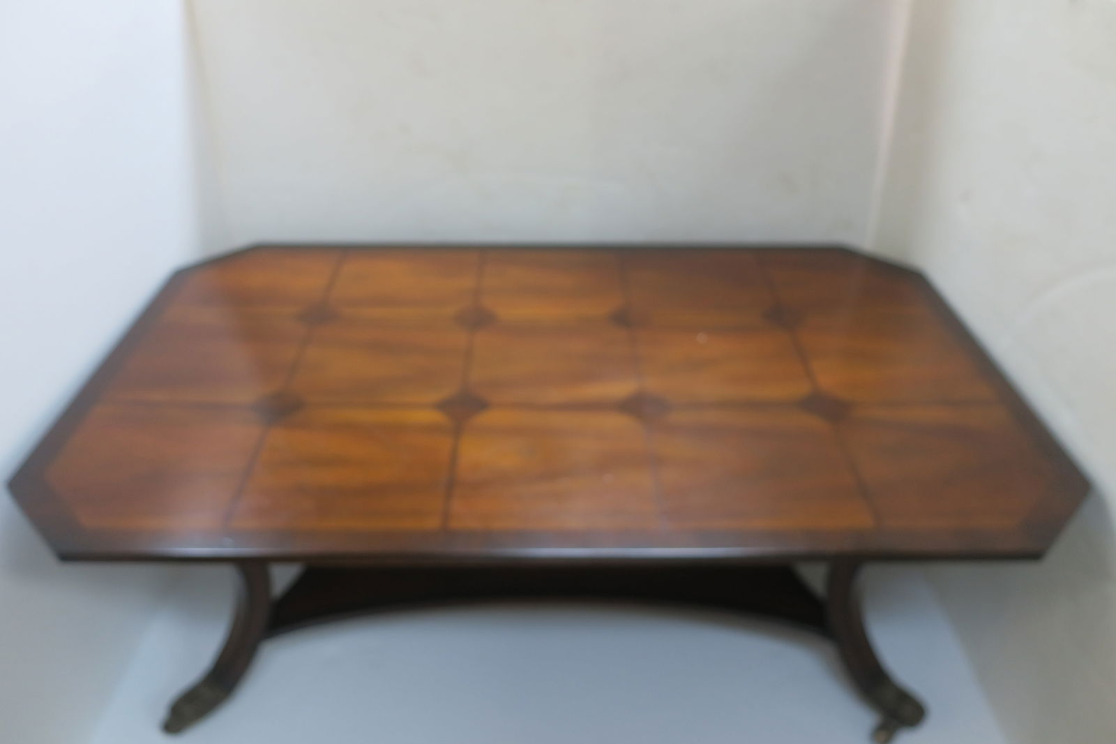Inlaid Mixed Wood Coffee Table:: Inlaid Mixed Wood Coffee Table: Cut Corner Top Table with Lower Shelf, Curving Legs with Brass Capped Feet and Casters. Lighter Squares with Inlaid Darker Lines and Diamond Shapes. 20"T, 32" X 52". (2