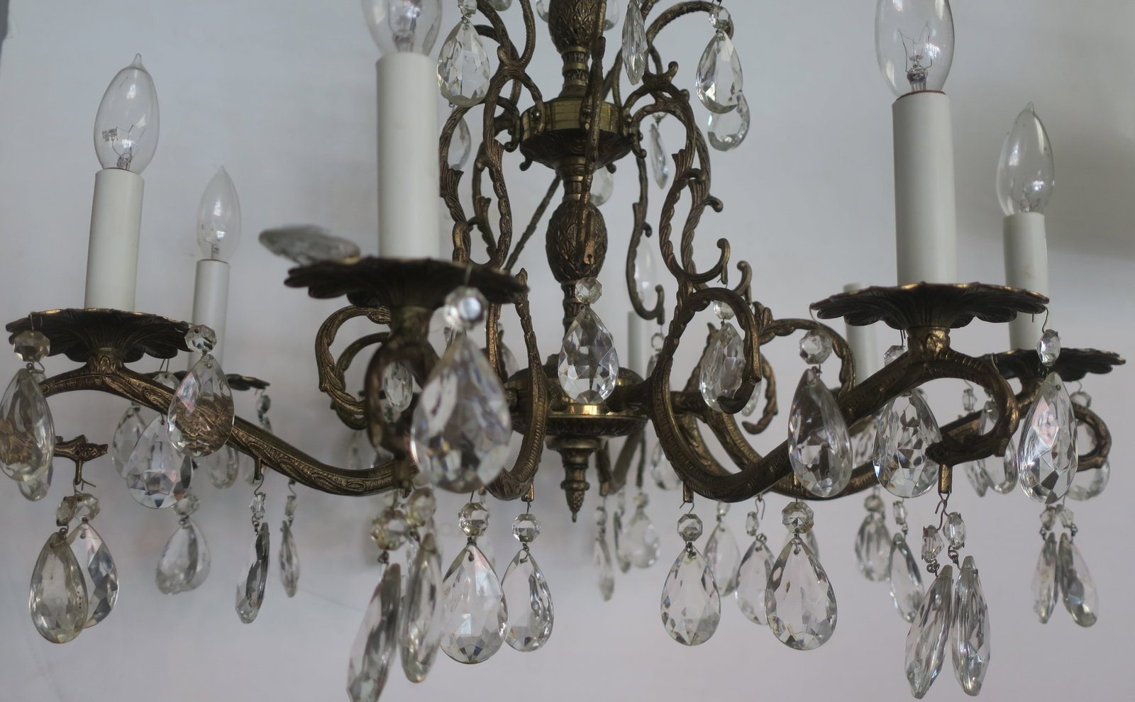 Eight Arm Bronze and Crystal Chandelier:: Eight Arm Bronze and Crystal Chandelier: Relief Fashioned Canopy with Turned Center Stem Supporting 8 Sinuous Leafy S Shaped Arms. Teardrop Faceted Prisms are Draped From Candle Cups and Branch. Culmi