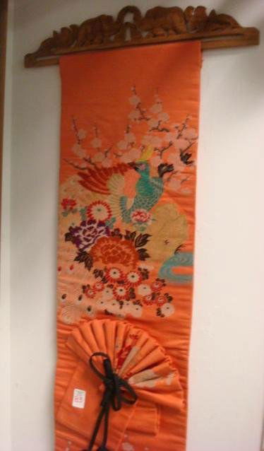 Hand Stitched Asian Silk Wall Hanging: Hand Stitched Asian Silk Wall Hanging: Gilt Embellished Colorful Peacock in Ming Tree. On Salmon Field Fabric with Fan and Scarf Applied to Front. Pierced Wooden Carved Holder on Top For Hanging. 12"