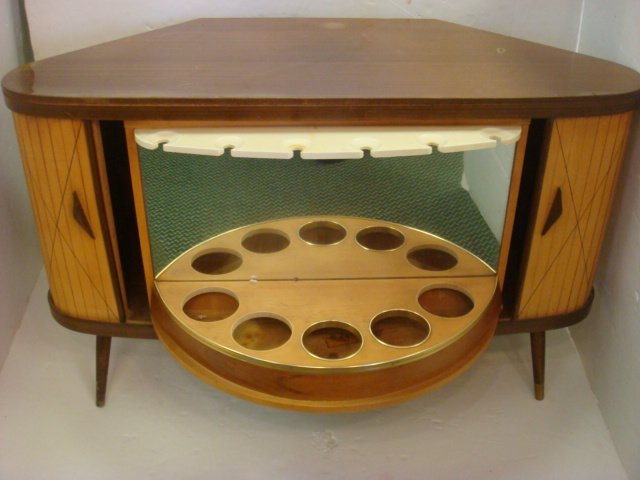 Mid-Century Moderne Revolving Bar/Bookcase:: Laminated Top, Fruit Wood Slaed Tambour Sides open to Bar with Bottle and Glass Holderswhich Rotates becoming Small Bookcase. 27" x 43" x 27". Fits into corner. Round Tapered Legs with Brass caps. Ver