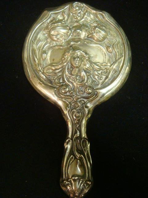 Art Nouveau Figural Silver Plate Hand Mirror: Art Nouveau Figural Silver Plate Hand Mirror: Beveled Mirror Set Securely with Embossed Design of Female with Swirling Hair and Floral Detailing. 10"L, 5 1/4"D. Some dings and Mirror Discoloration. (1