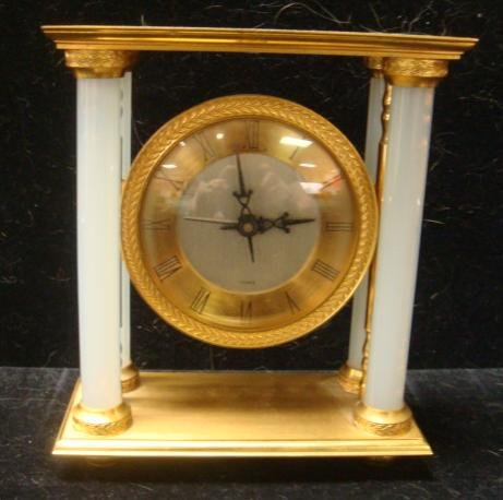 J.E.CALDWELL Brass French Boudoir Clock:: J.E.CALDWELL Brass French Boudoir Clock: Four Opalescent Free Standing Crystal Columns on Footed Frame. Round Suspended Clock with Metal Face, Roman Numerals. Floral Garlands Cap Columns & Surround Fa