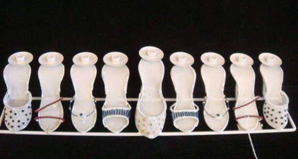 Novelty Metal and Mesh High Heel Menorah:: Novelty Metal and Mesh High Heel Menorah: White Metal Rod Base Features 9 High Heel Shoes, Each Supporting a White Enamel Candle Cup. Larger Scale Shoe Elevates the Center. By Copa Judaica. (100-140)