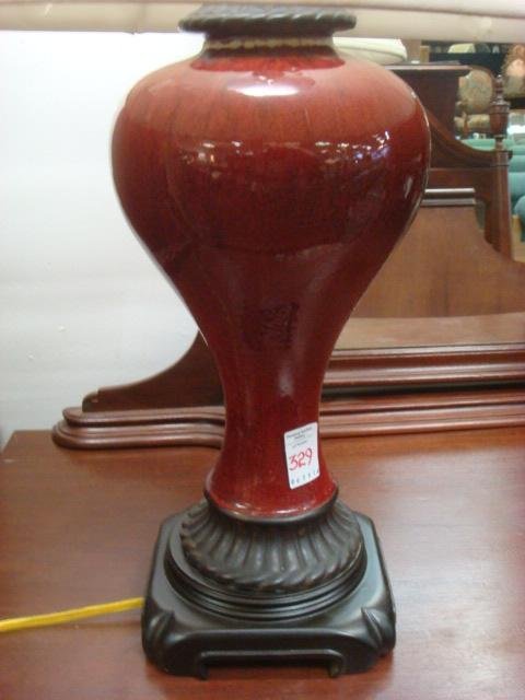 Oxblood Vase Shaped Table Lamp on Wooden Base:: Oxblood Vase Shaped Table Lamp on Wooden Base: Ceramic Lamp with Mottled Gloss Glaze. 28"T with Pineapple Finial. Set on Asian Inspired Base. Linen Shade with Some Damage. (60-80)
