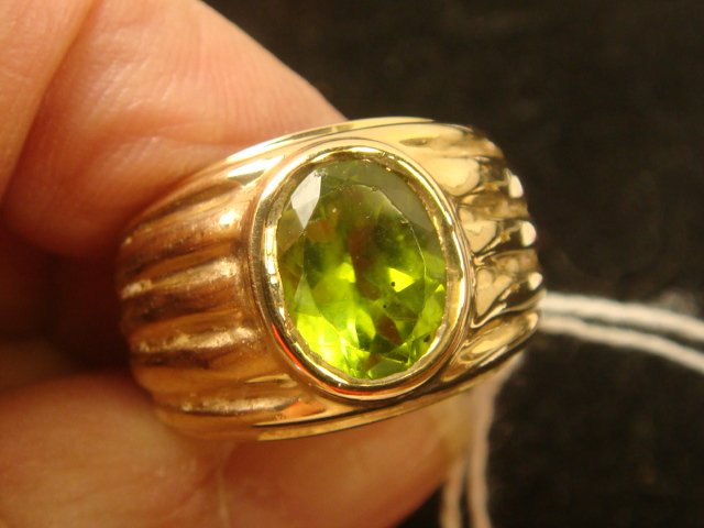 14K Yellow Gold Peridot Solitaire Ring:: 14K Yellow Gold Peridot Solitaire Ring: Oval Faceted Bezel Set Stone in Wide Ribbed Setting. Size 6 1/2. Total Weight 7.4gr. (400-700)