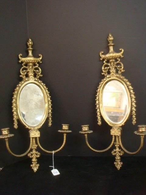 Pair of Hollywood Regency Double Arm Brass Sconces:: Pair of Hollywood Regency Double Arm Brass Sconces: Vintage Sconces with Beveled Mirror (Some Spots), Cupped Candle Holders with Fluted Details. Urn/Flame Crest with Draped Bell Flowers at Sides. 24"L