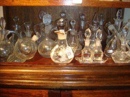 Collection of Glass Cruets, CA 1930:: Collection of Pressed Glass Cruets, One Mary Gregory: 18 Glass Cruets with Stoppers. Some with Original Labels. One has Mary Gregory Painting & 2 Have Trays. Various Styles and Sizes. CA 1930. 