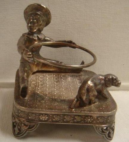 Rare James Tufts Silver-plate Buster Brown Cup Holder:: Rare James Tufts Silver-plate Buster Brown Cup Holder: Squared, Footed Base has Buster Brown Seated in One Corner Holding a Hoop with his Dog Tige Standing at other Corner. Marked on Bottom James W Tu